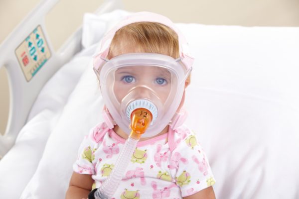 Philips Respironics PerforMax klein - Kleines Kind mit Beatmungsmaske sitzt in Bett.