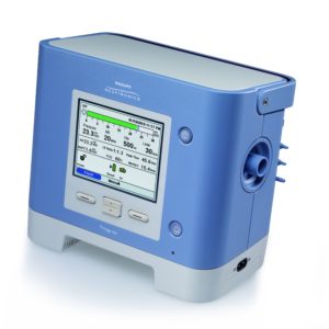 Das Beatmungsgerät Philips Respironics Trilogy 202 wird von vorne dargestellt. Sein Display zweigt die gemessenen Atmungsparameter an. Frontalansicht